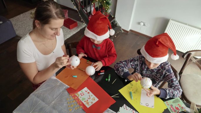 家庭用彩纸、闪光片和硬纸板制作圣诞装饰品的俯视图。寒假，家人团聚，孩子和父母一起庆祝