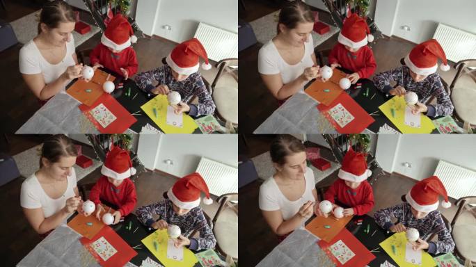 家庭用彩纸、闪光片和硬纸板制作圣诞装饰品的俯视图。寒假，家人团聚，孩子和父母一起庆祝