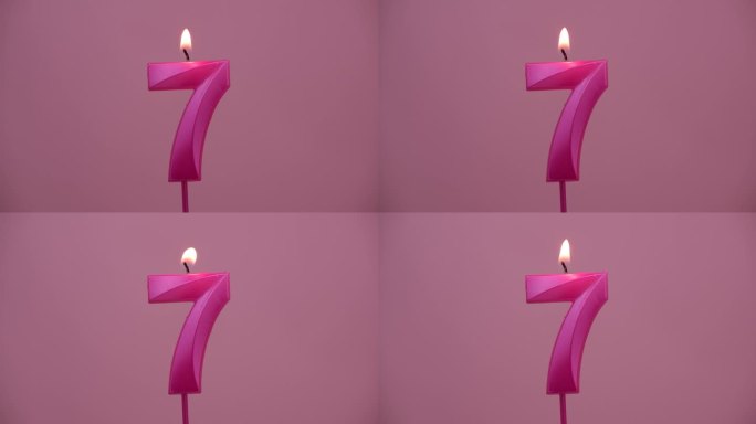 燃烧的生日蜡烛在粉红色的背景，7号。