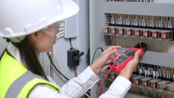 电工工程师工作测试仪，用于测量电气控制柜中电力线路的电压和电流。电力和电气维修服务。