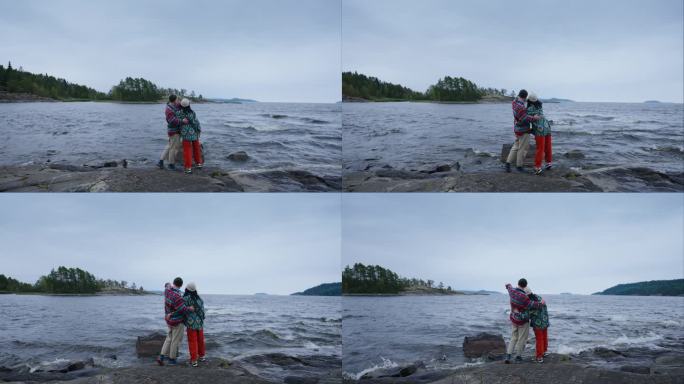 一对恋人站在美丽的湖边，男友拥抱女友，背影