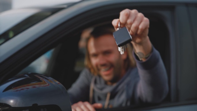 画像上快乐的男人站在窗口，摇着新车的车钥匙