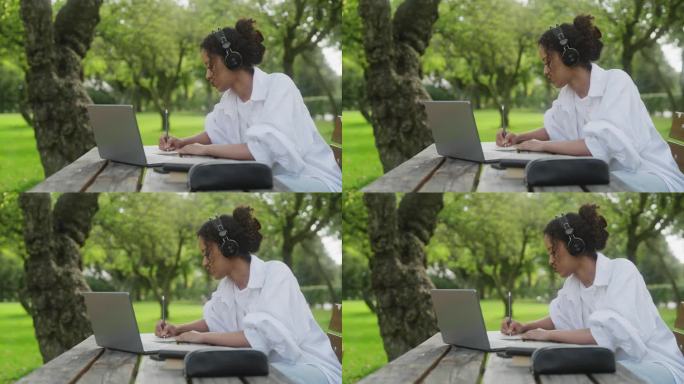 一个女人在公园里学习，在她的笔记本上写字