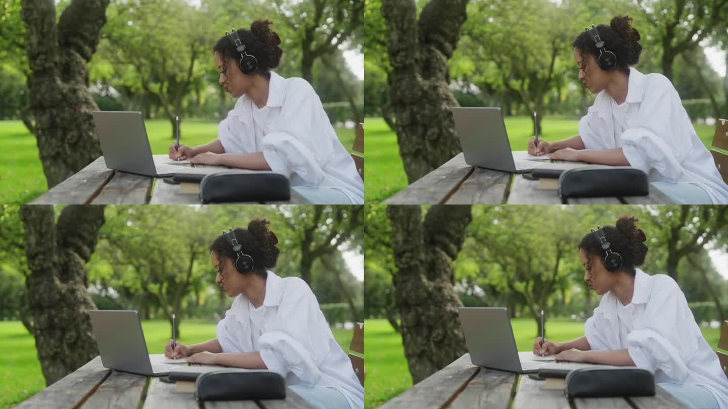 一个女人在公园里学习，在她的笔记本上写字
