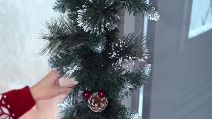 公寓门口装饰的圣诞树花环，女性的手正在拉直的特写镜头;