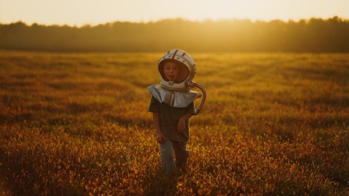 夏天，无忧无虑的小男孩戴着太空人服头盔在野外玩耍
