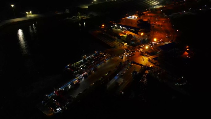 航拍无人机在夜间从轮渡前到轮渡侧的轨道上运行，当时汽车正在装载货物
