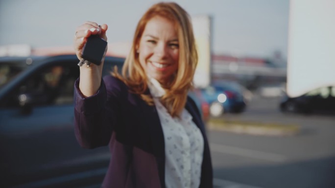 图为自信的女汽车销售员在停车场拿着车钥匙