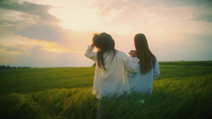 夕阳下，年轻的女性朋友们微笑着站在绿色的麦田里