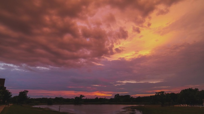 紫粉和红色的风暴云在池塘上空蔓延，时间流逝