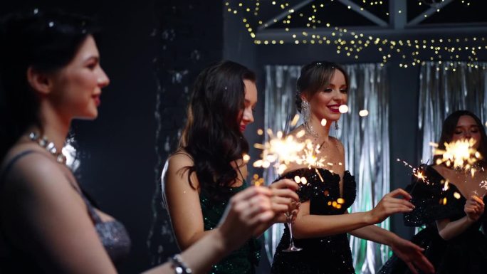 不同的妇女手持燃烧的烟花在圣诞之夜，庆祝2024年新年的肖像