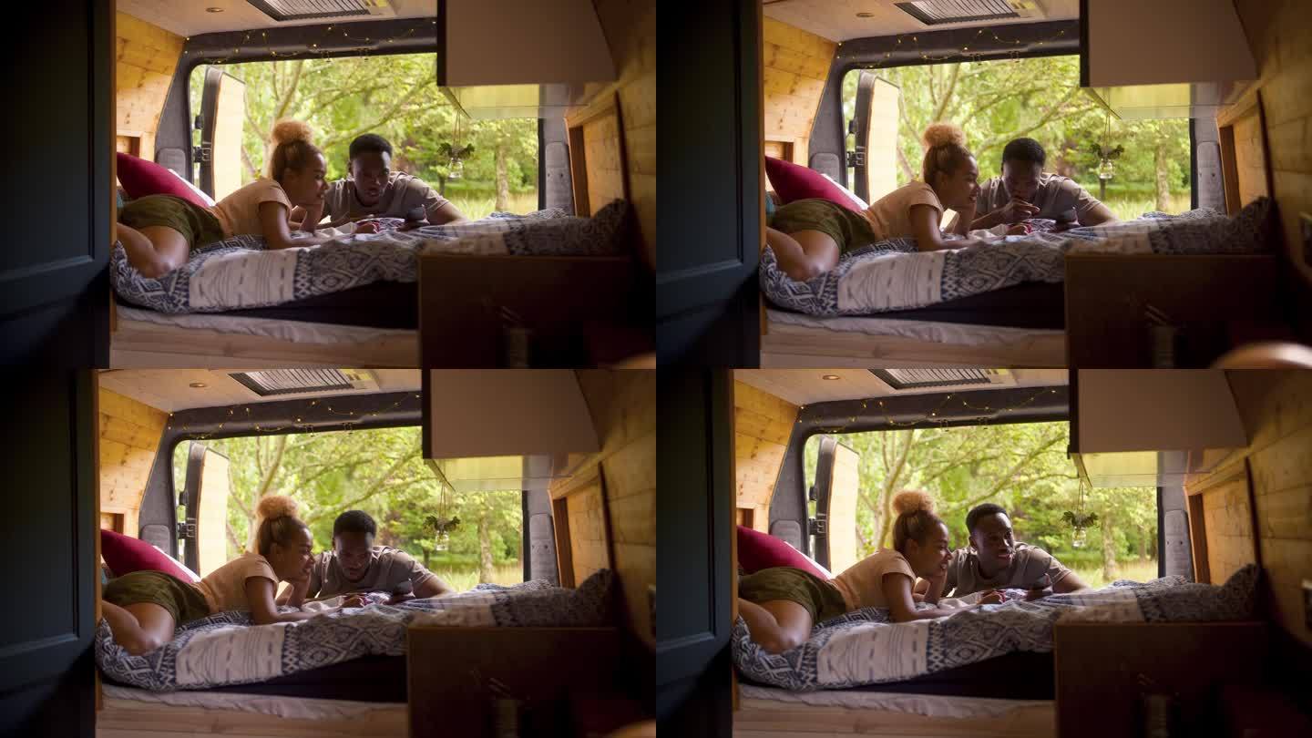 一对夫妇在乡村露营，在房车里放松，一起看手机