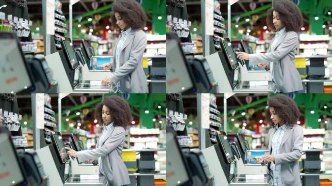 一位女顾客在超市使用自助收银台结账。