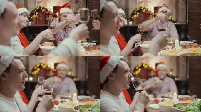 快乐的家庭聚会，在圣诞节假期和庆祝祝酒碰杯红酒和各种食物在桌子上，如烤鸡，蔬菜沙拉，油炸土豆在装饰的