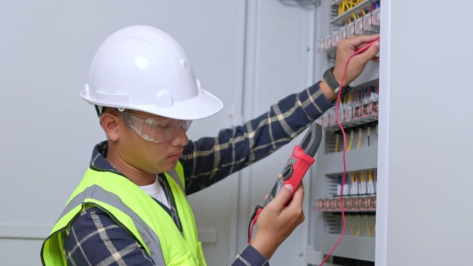 电工工程师工作测试仪，用于测量电气控制柜中电力线路的电压和电流。电工用万用表测量控制面板上的电流。