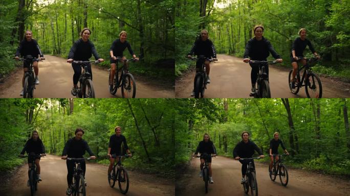 三个快乐的女孩朋友在大自然中骑自行车，一群女运动员在夏天的森林里骑自行车