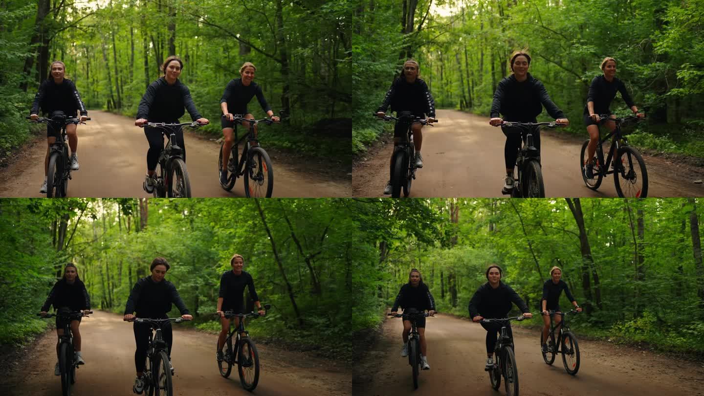 三个快乐的女孩朋友在大自然中骑自行车，一群女运动员在夏天的森林里骑自行车