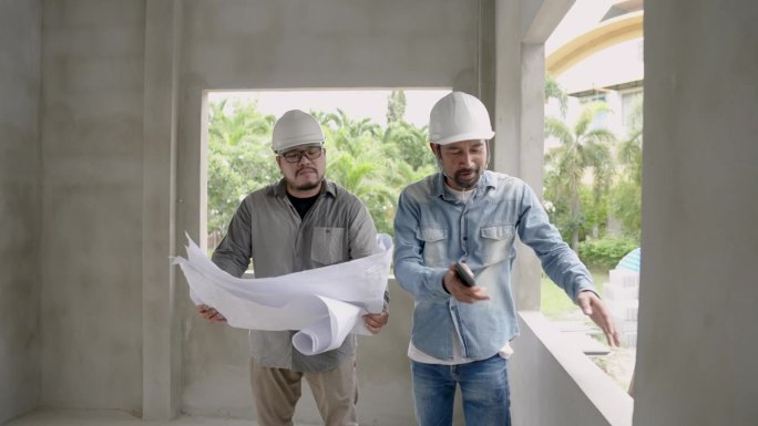 亚洲建筑监理爬上梯子，指出问题所在。咨询一位留着胡子、戴着头盔的印度工程师