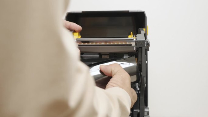近距离人手插入条形码不干胶或标签不干胶或热敏色带卷条形码打印到条形码打印机。