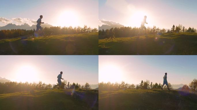 特写，镜头光晕:男跑步者和他的狗沿着风景秀丽的山顶奔跑