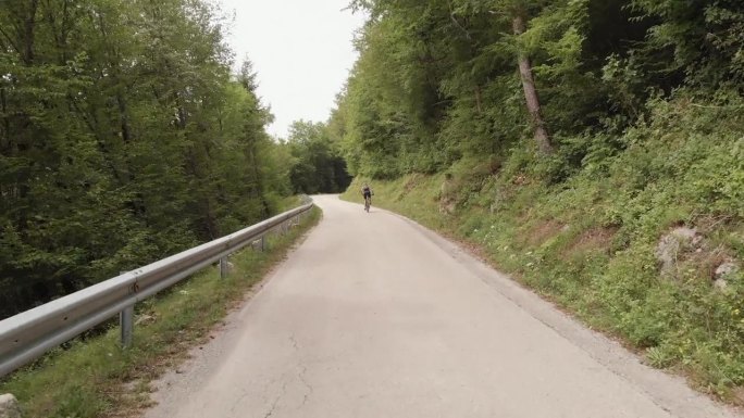 骑山地自行车的人在安静的道路上穿过乡村