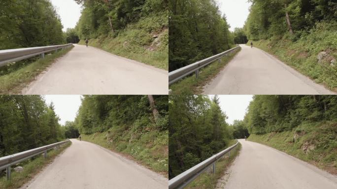 骑山地自行车的人在安静的道路上穿过乡村