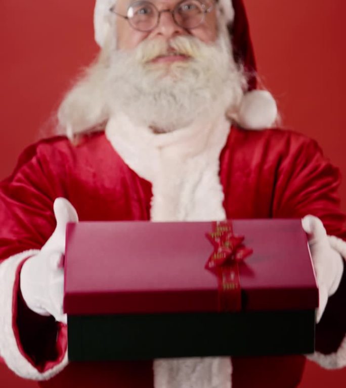 快乐的圣诞老人拿着用丝带装在红盒子里的圣诞礼物