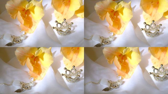 钻石银皇冠，珠宝和黄色的花朵在白色丝绸背景。豪华背景，婚礼，周年纪念，生日