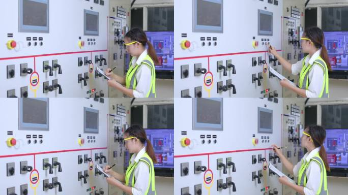 操作员电气工程师在开关室用笔记本记录配电板的电压、电流和功率