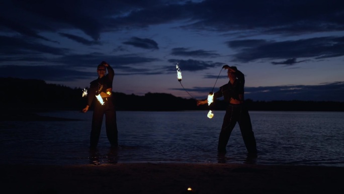 勇敢的女人们在河岸边与火共舞，神秘的火在湖岸表演