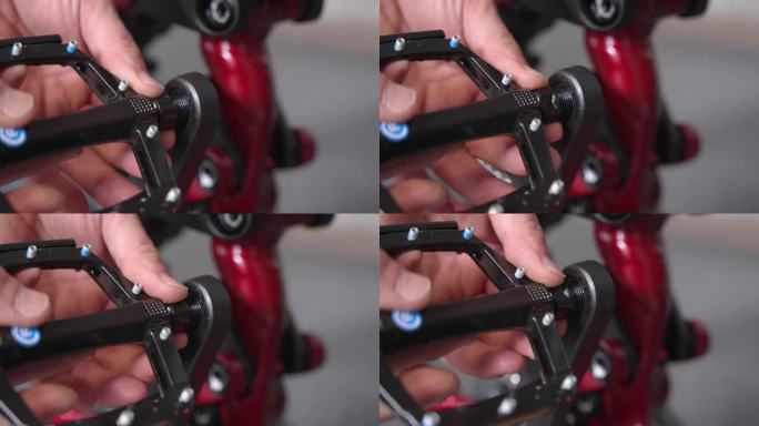 由自行车修理工在全新的山地车的曲柄臂上安装带脚钉的平踏板。特写镜头