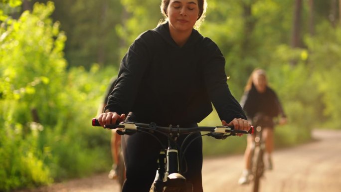 少女和她的朋友骑自行车在美丽的自然保护区公园在夏天的一天，肖像