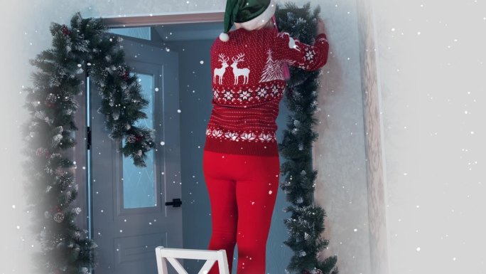 身着红色传统服装，椅子上绣着站着的鹿的妇女用圣诞树花环装饰门口。