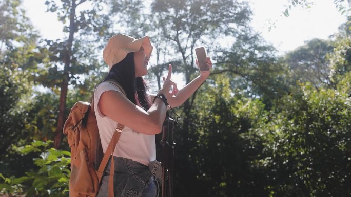 徒步旅行者有吸引力的快乐的年轻女孩背着背包在山上徒步旅行，周围都是令人惊叹的风景