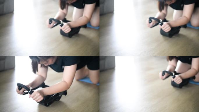 一名穿着运动服的亚洲女性正在家里的瑜伽垫上使用健身车来增强腹部肌肉，以保持健康。