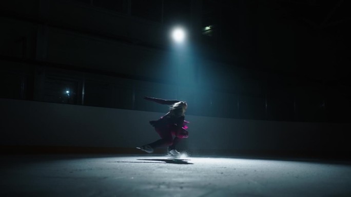 才华横溢的女子花样滑冰运动员的剪影在溜冰场上旋转在明亮的柔和的光，慢动作