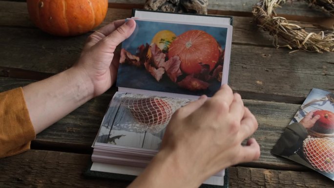 女性的手翻看着印有秋天照片的相册。