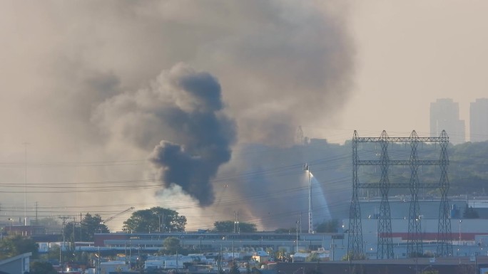 装有空中塔的消防车在工厂大楼的大火上喷水