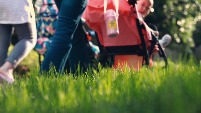 年轻妈妈小区公园草坪推婴儿车遛娃