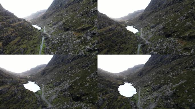 电影般的无人机镜头穿过Dunloe峡谷，露出岩石悬崖后面的一个小池塘