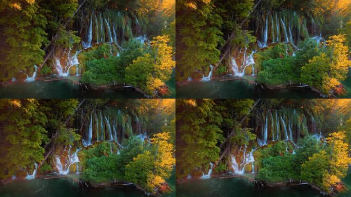 在温暖的夕阳下，五彩缤纷的瀑布在国家公园的秋天森林中流淌。瀑布在树林里与橘子树和淡水。