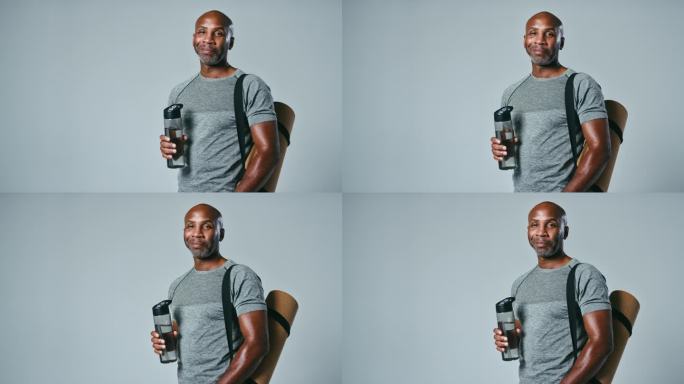 工作室肖像成熟的男人在健身房健身服装与运动垫和水瓶