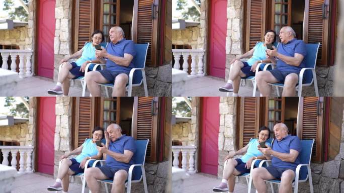 一位老人在酒店或房子的阳台上用手机给他的妻子看东西