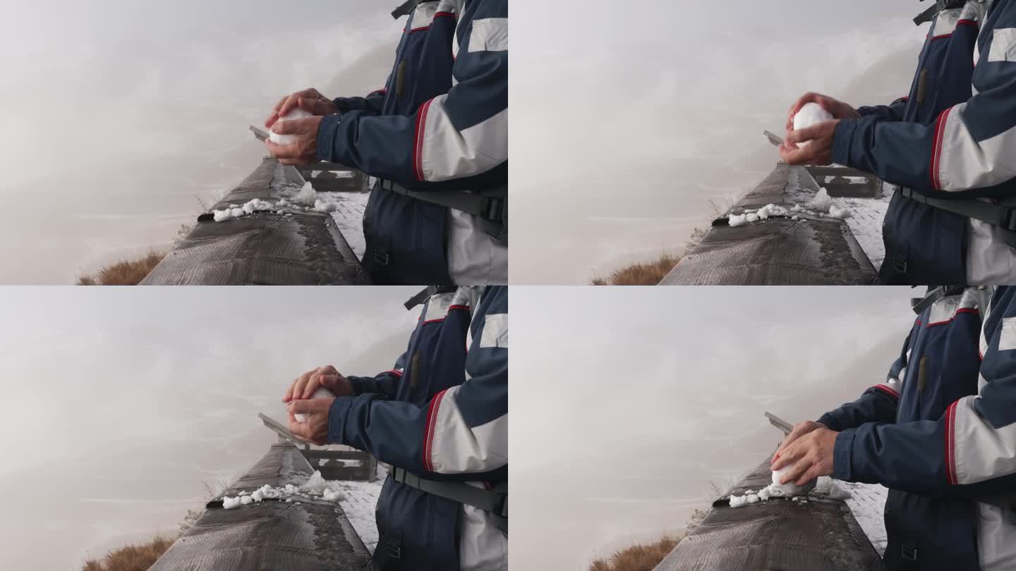男人们的手在木栏杆上滚动着一个雪花玻璃球，背景是雾中的山脉