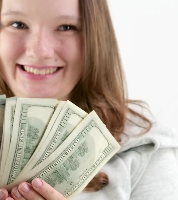 一个少年的快乐第一次钱赚了很多美元100美元的钞票一捆一个女孩在框架里展示钱笑笑开心地张开嘴一个好礼