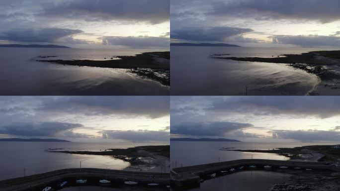 无人机在平静的戈尔韦湾和巴纳码头上撤退，反射黄昏的夕阳