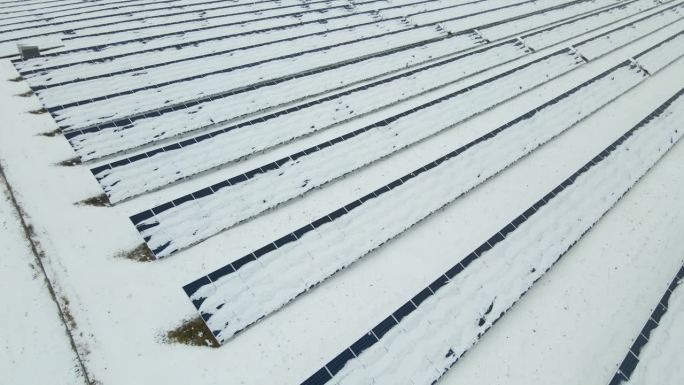 可持续性发电厂鸟瞰图，冬季太阳能光伏板被雪覆盖，用于生产清洁能源。北方可再生电力效率低的概念