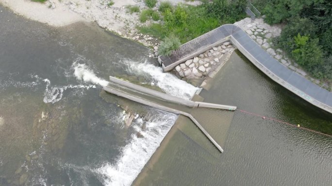水顺着人造堤坝顺流而下，独木舟滑向河中。——空中