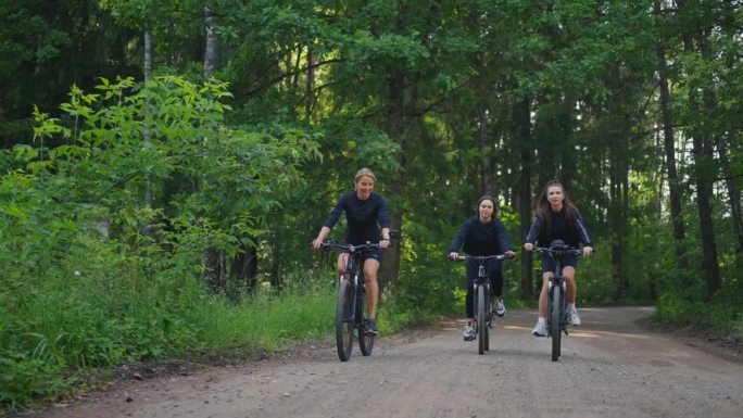 三个女孩朋友在美丽的夏日清晨骑自行车，体育活动