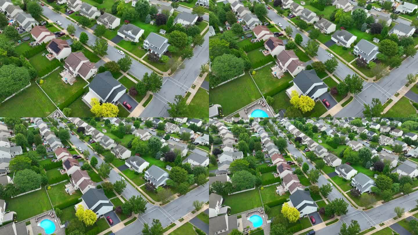 夏天的美国社区。空中旋转显示的广阔的住宅开发与绿树成荫的街道。住宅区的太阳能电池板和草坪。